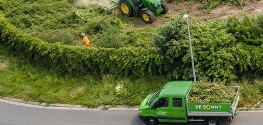 Tractor van De Ronny klepelt hoog gras op een bedrijventerrein